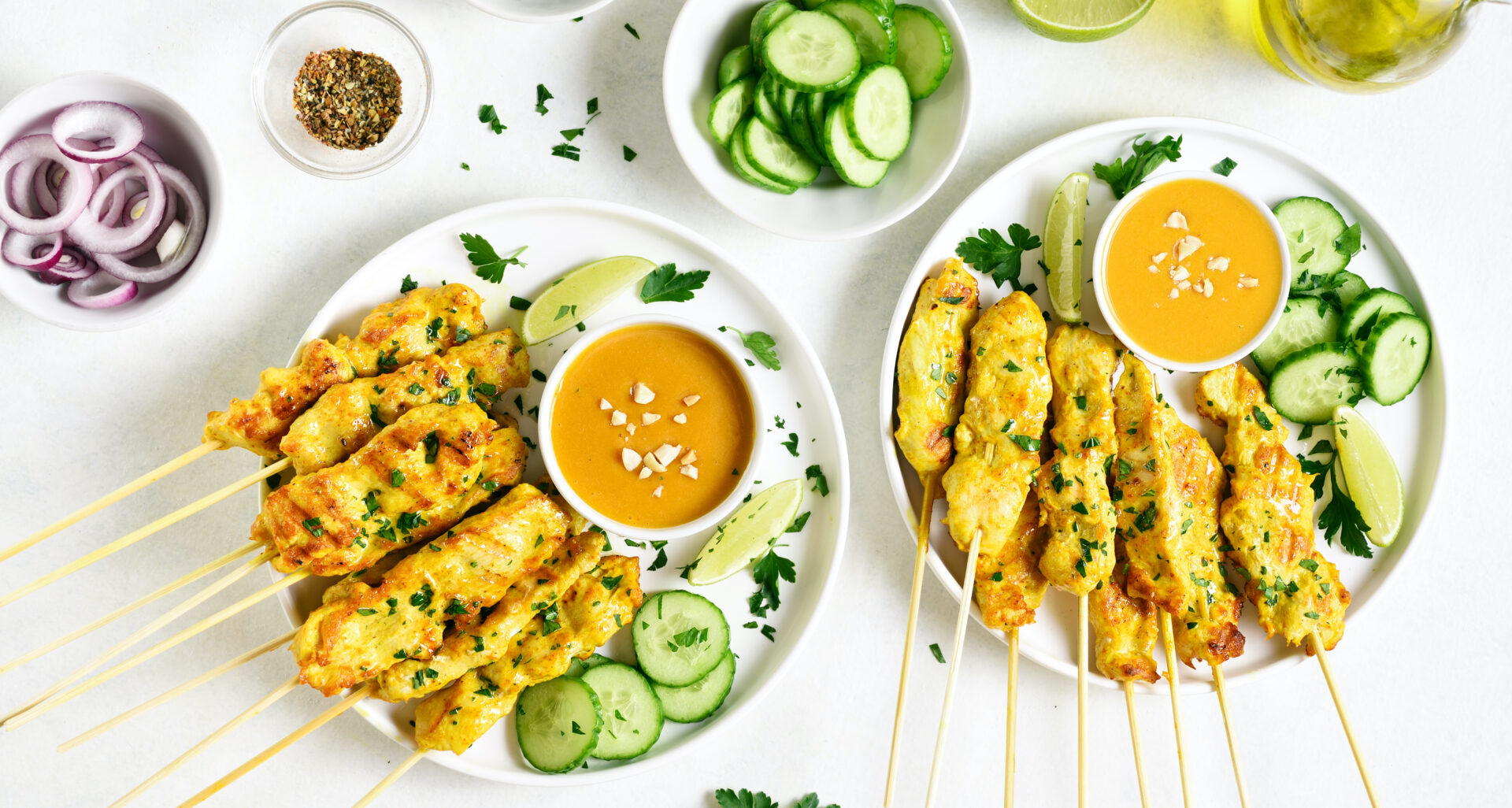 chicken seekers on a white plate with peanut satay sauce in small bowls